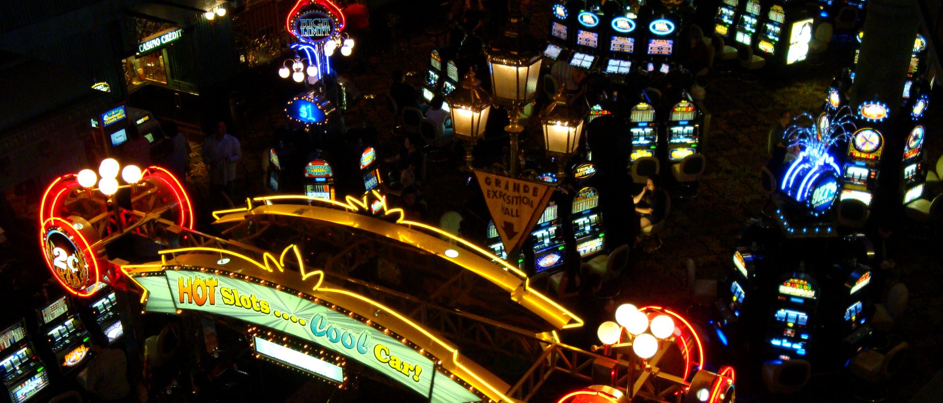 Rangées de machines à sous sous des néons dorés et rouges, dans une salle de casino